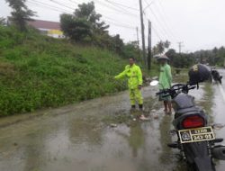 Bhabinkambitmas Polsek Pasangkayu Memantau Luapan Air Yang Merembes Sampai Kebahu Jalan
